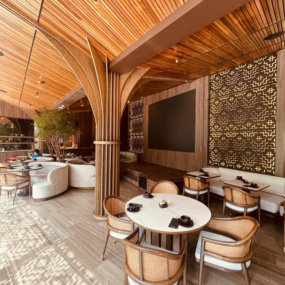 Comedor del Hotel Binn en Medellín al mediodía, con techos de madera, luz cálida y mesas listas para el almuerzo