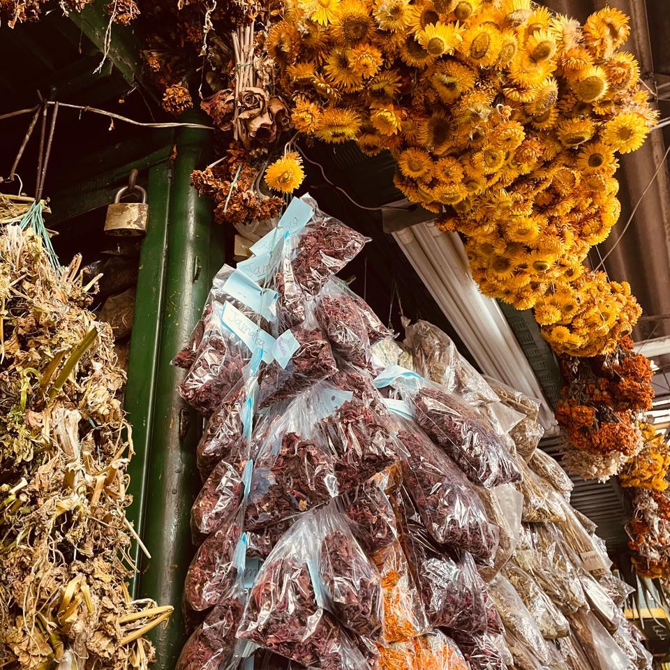 Puesto de remedios naturales en la Plaza Minorista de Medellín, con cartel que promociona gotas para los piojos