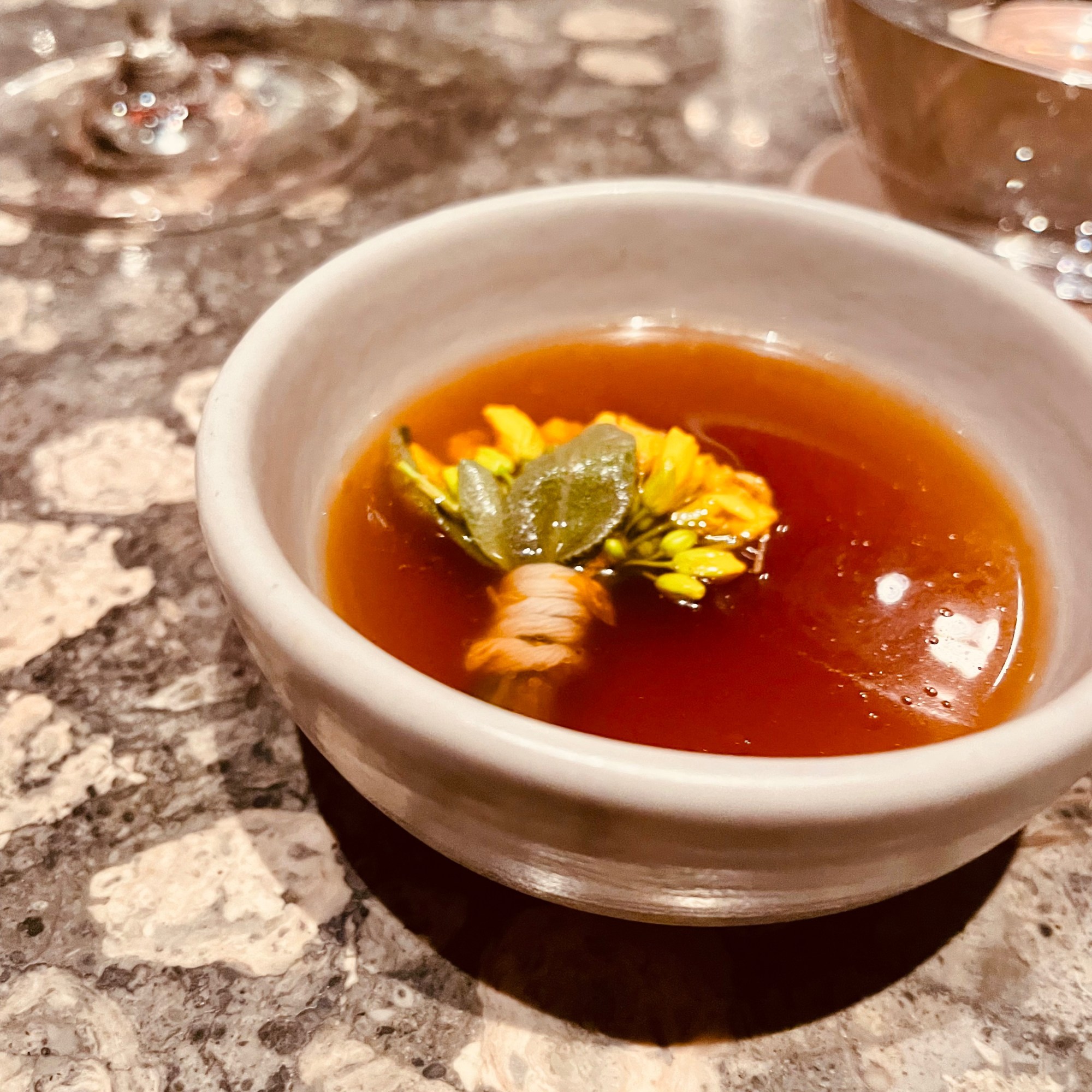 Plato de caldo de pandam con cúrcuma y melocotón ahumado en El Chato, Bogotá